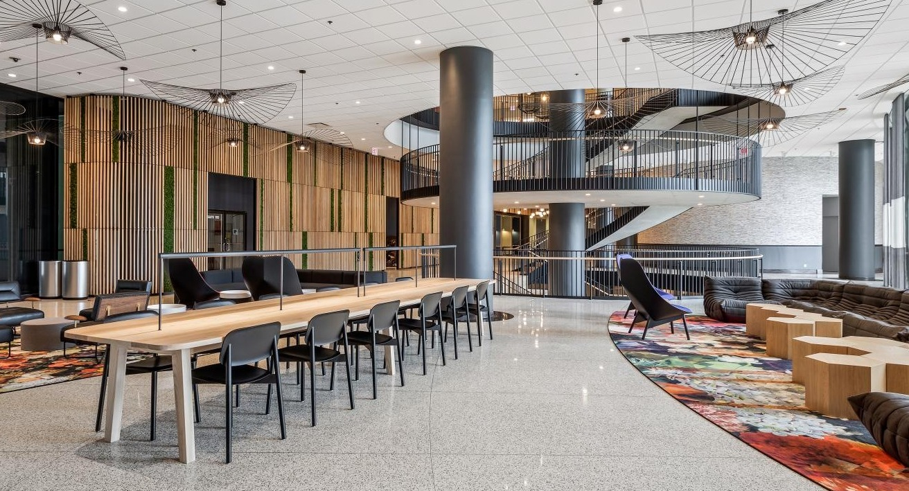 Grand amenity space with a communal table, multiple lounge areas, and a striking spiral staircase at River City Apartments in Chicago