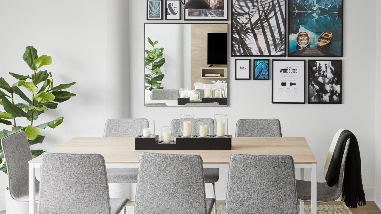 A cozy dining area with modern grey chairs, a light wood table, and an accent wall with varied artwork at River City Apartments in Chicago