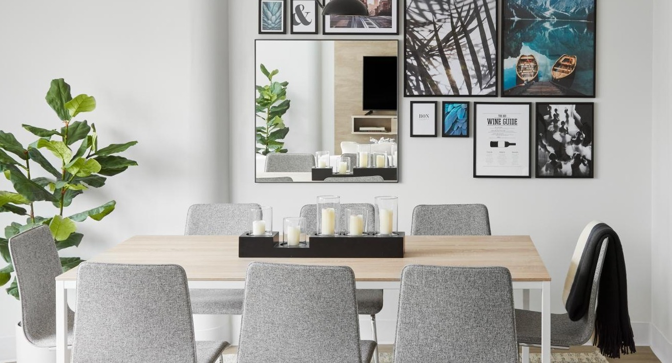 A cozy dining area with modern grey chairs, a light wood table, and an accent wall with varied artwork at River City Apartments in Chicago