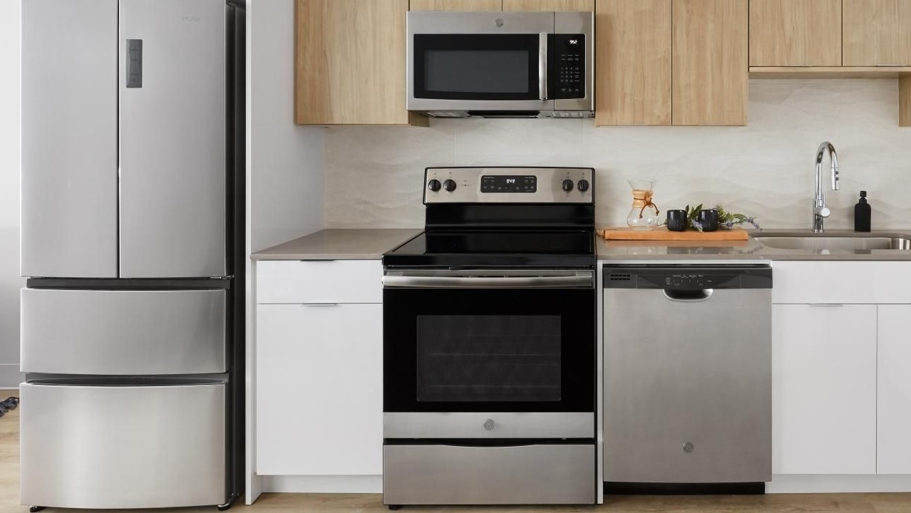 A contemporary kitchen featuring stainless steel appliances, light wood upper cabinets, and white lower cabinets at River City Apartments in Chicago