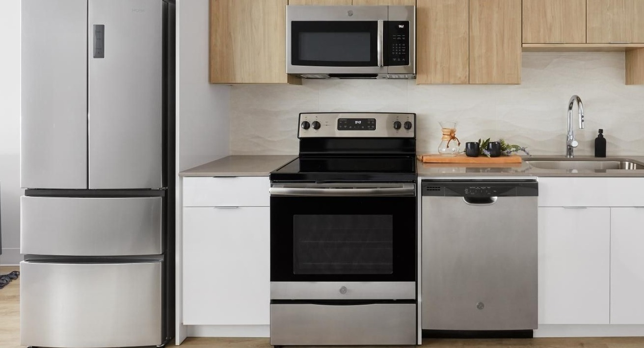 A contemporary kitchen featuring stainless steel appliances, light wood upper cabinets, and white lower cabinets at River City Apartments in Chicago