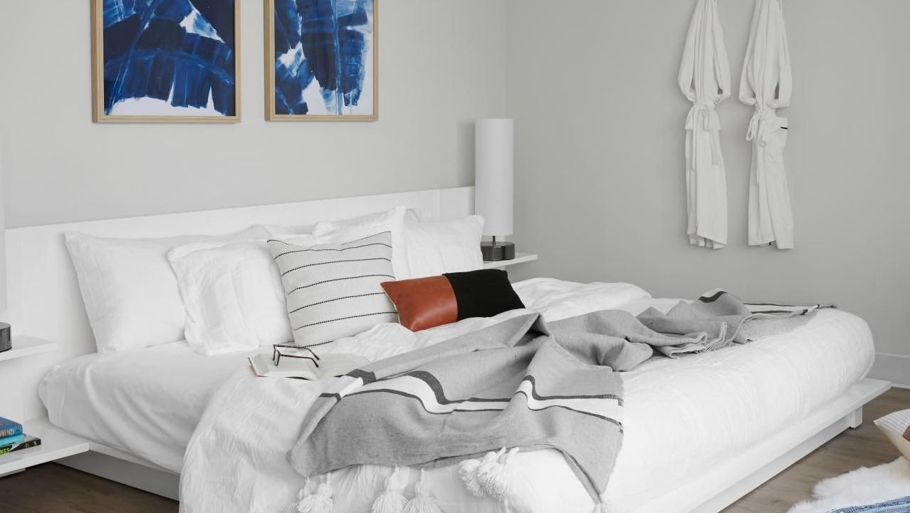 Serene bedroom with a white bed, abstract blue artwork, and clean lines, creating a peaceful retreat at River City Apartments in Chicago