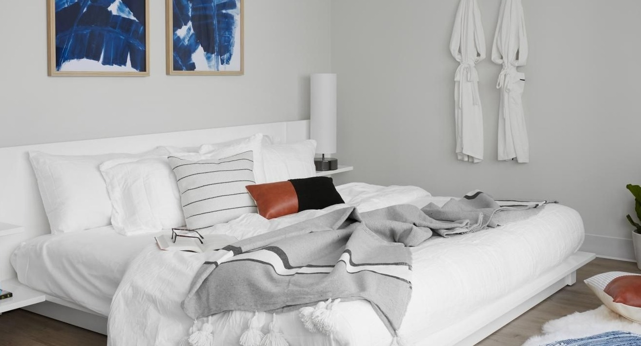 Serene bedroom with a white bed, abstract blue artwork, and clean lines, creating a peaceful retreat at River City Apartments in Chicago