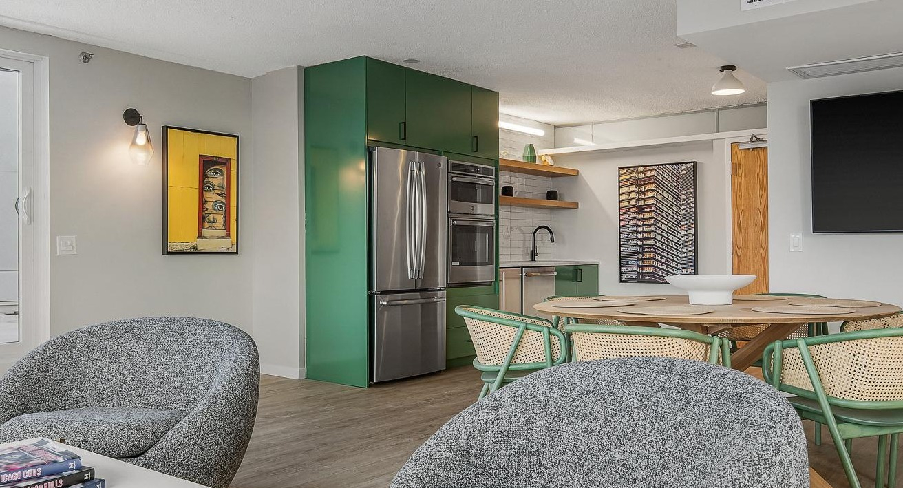 Unique kitchen and dining area featuring vibrant green cabinets, stainless steel appliances, and a round dining table at River City Apartments in Chicago