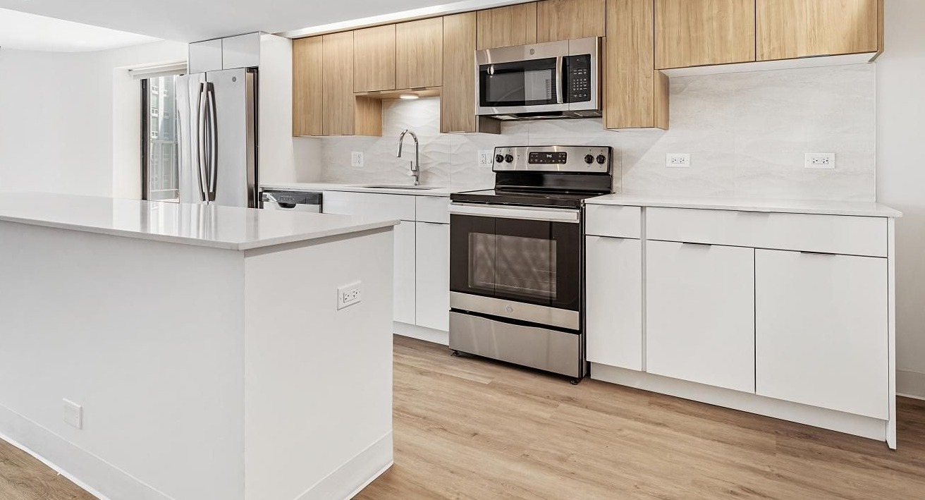 Bright kitchen with light wood cabinetry, white countertops, stainless steel appliances, and a central island at River City Apartments in Chicago