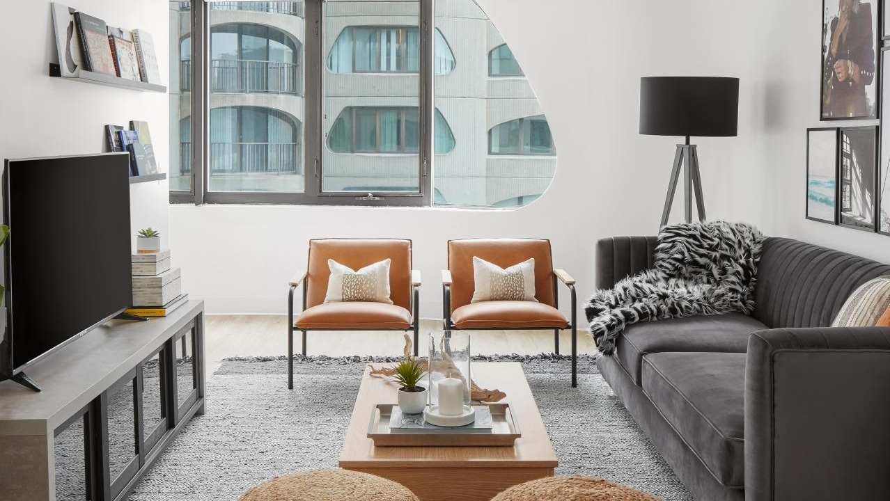 Inviting living room with a dark sofa, two leather armchairs, and comfortable ottomans, creating a cozy atmosphere at River City Apartments in Chicago