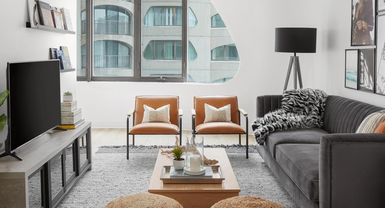 Inviting living room with a dark sofa, two leather armchairs, and comfortable ottomans, creating a cozy atmosphere at River City Apartments in Chicago