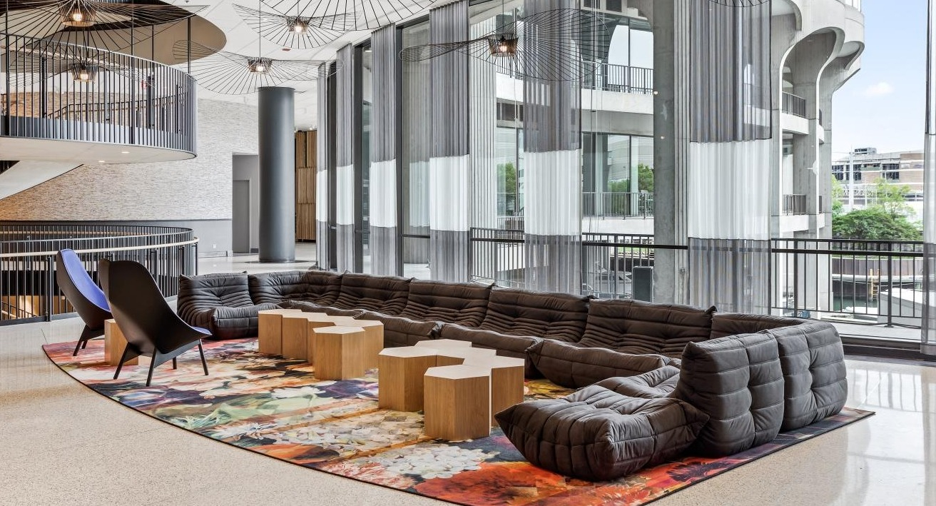 Spacious lobby lounge with diverse seating, a colorful rug, and a dramatic spiral staircase at River City Apartments in Chicago