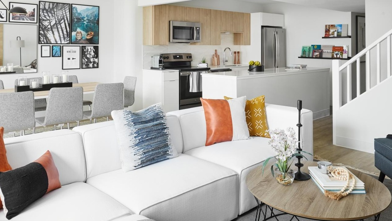 Open-concept living and dining area with a white sectional, dining table, and modern kitchen visible in the background at River City Apartments in Chicago