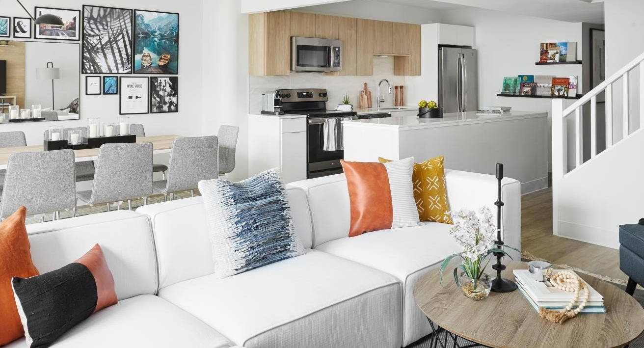Open-concept living and dining area with a white sectional, dining table, and modern kitchen visible in the background at River City Apartments in Chicago