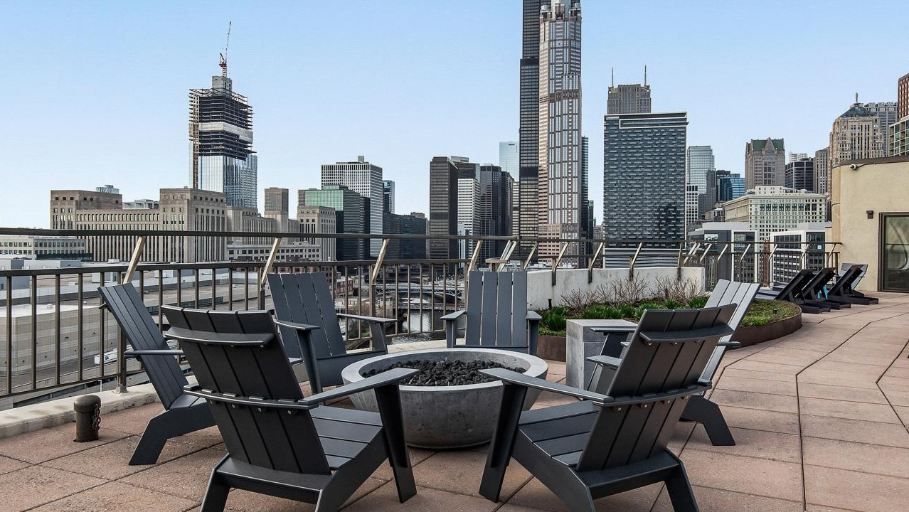 Inviting rooftop terrace with a fire pit, Adirondack chairs, and stunning views of the Chicago skyline at River City Apartments in Chicago