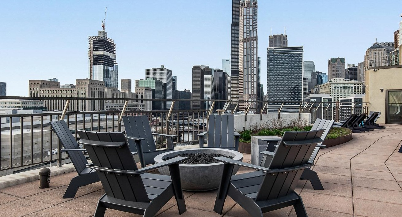 Inviting rooftop terrace with a fire pit, Adirondack chairs, and stunning views of the Chicago skyline at River City Apartments in Chicago