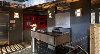 An elegant lobby entrance with a modern reception desk, sleek design elements, and illuminated cityscape artwork at River West Lofts in Chicago