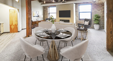 An industrial-chic living area with exposed brick, wooden beams, a modern dining set, and a comfortable lounge space at River West Lofts in Chicago