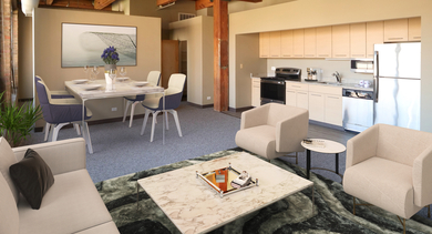 A spacious open-layout loft with exposed wooden beams, a modern kitchen, dining area, and living room at River West Lofts in Chicago