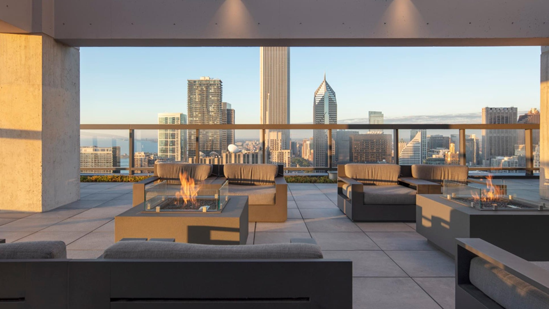 Rooftop lounge with modern firepits, cushioned seating, and sweeping Chicago skyline views at Optima Signature apartments