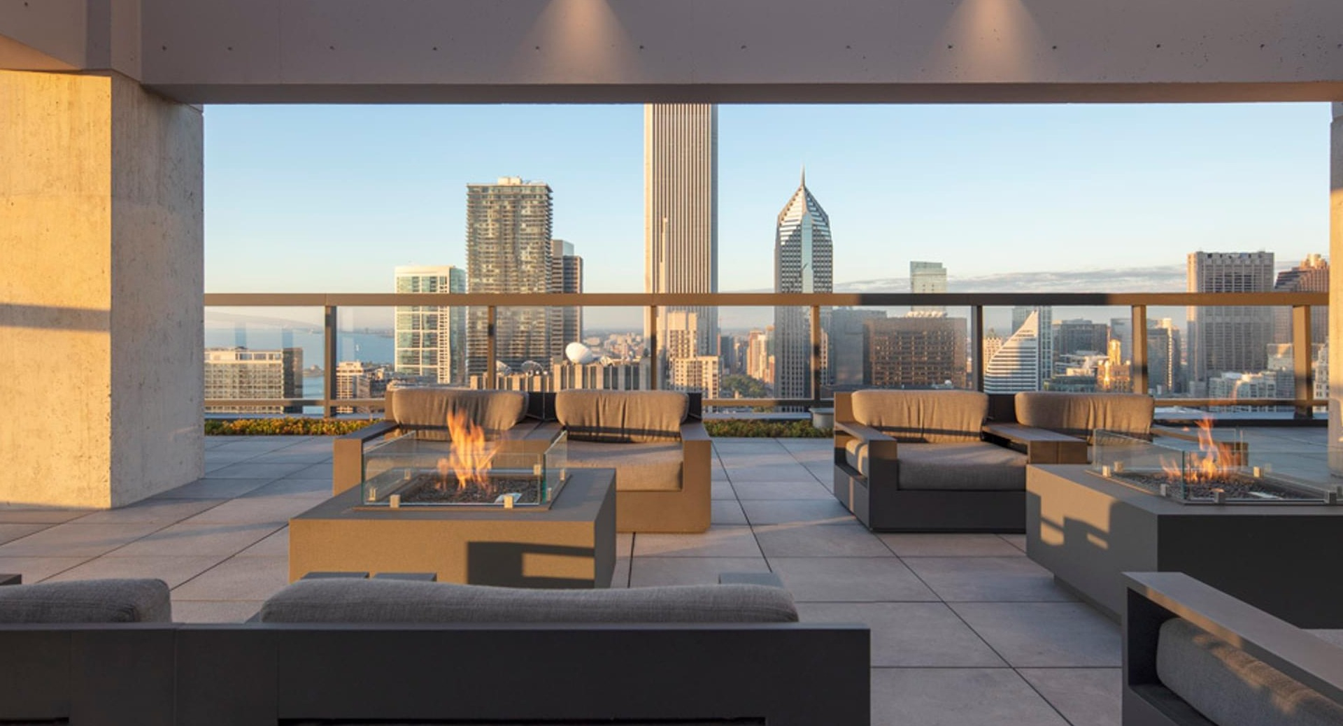 Rooftop lounge with modern firepits, cushioned seating, and sweeping Chicago skyline views at Optima Signature apartments