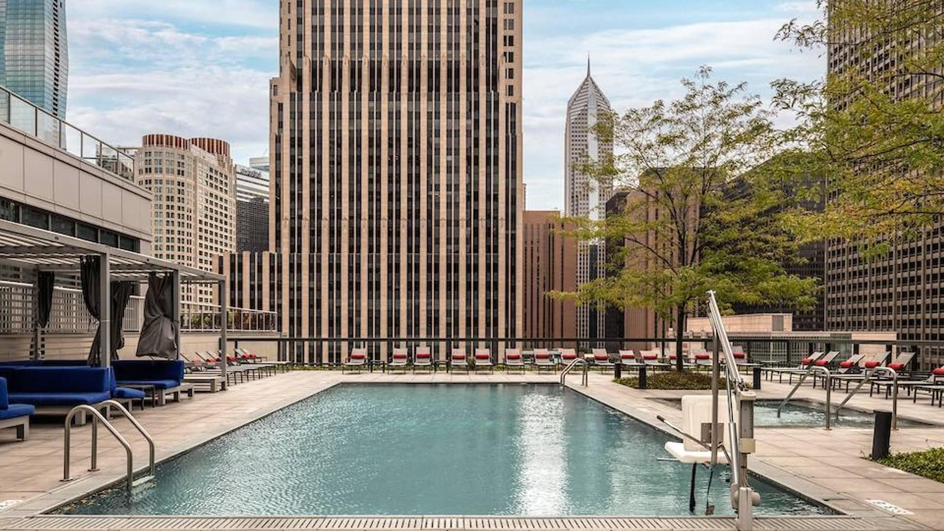 Rooftop swimming pool with skyline views, sun loungers, and shaded seating areas at Optima Signature apartments in Chicago