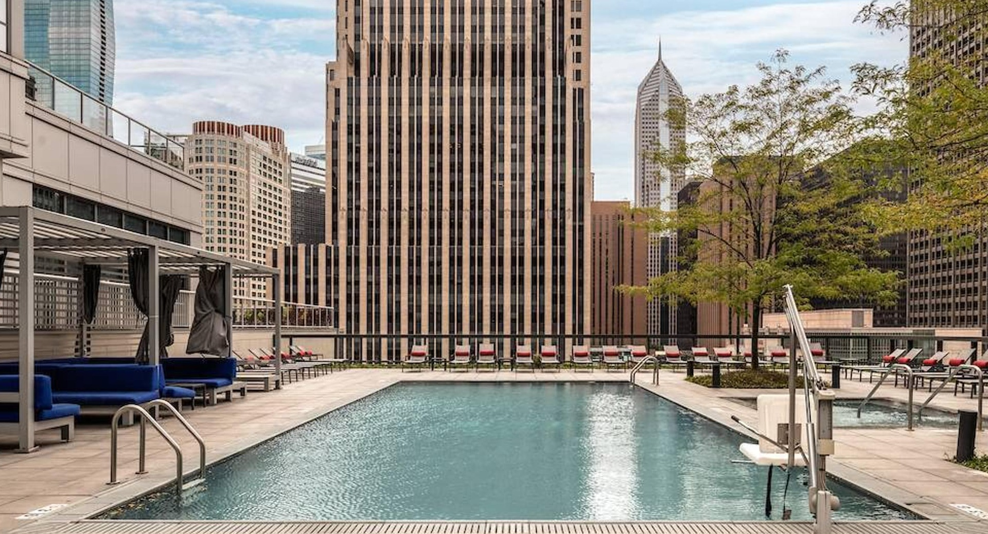 Rooftop swimming pool with skyline views, sun loungers, and shaded seating areas at Optima Signature apartments in Chicago