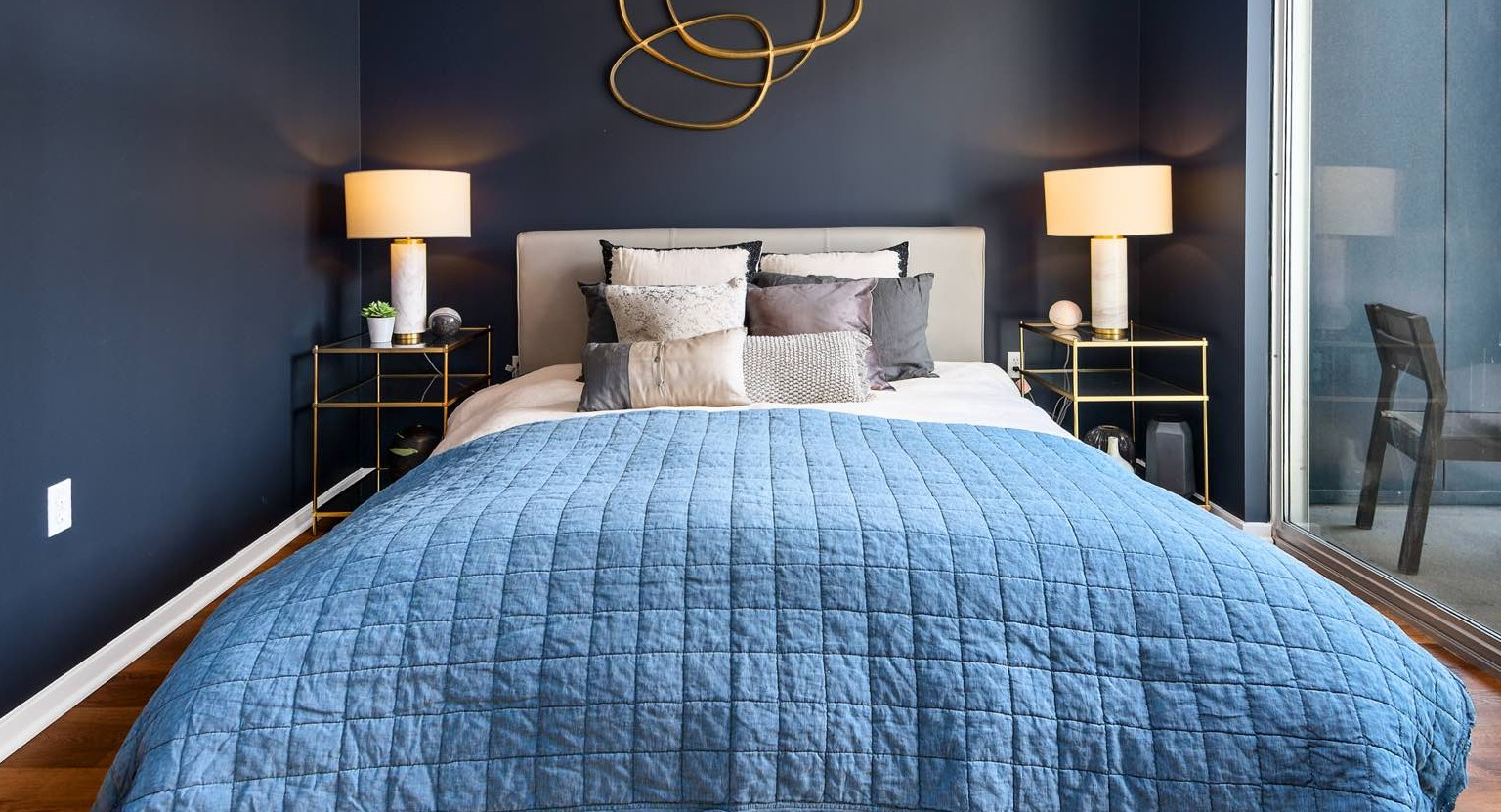 Stylish bedroom with a dark accent wall, elegant decor, and direct access to a private balcony with city views at Roosevelt Collection Lofts