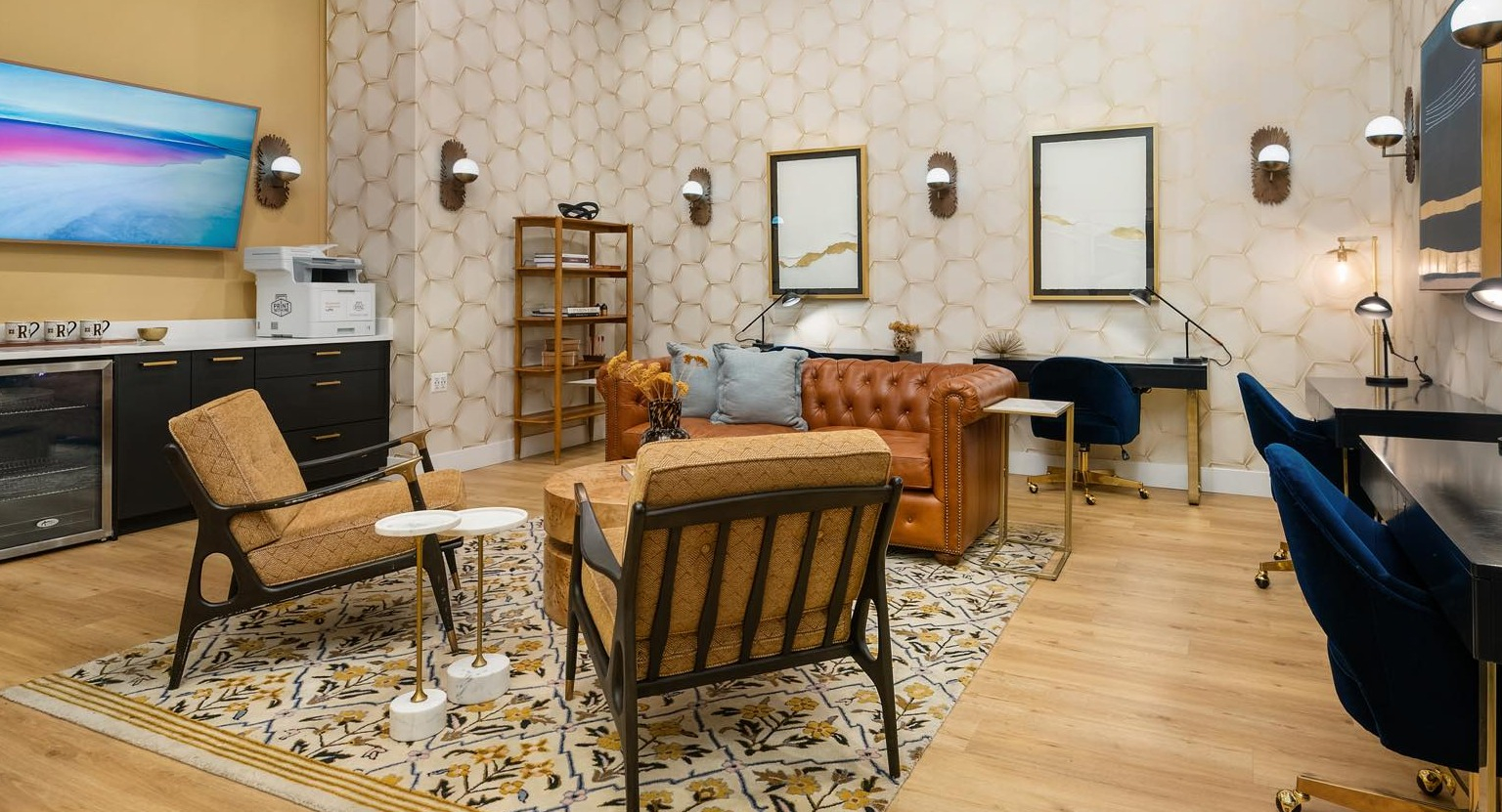Elegant business center and lounge with individual desks, comfortable seating, and a fully stocked bar area at Roosevelt Collection Lofts