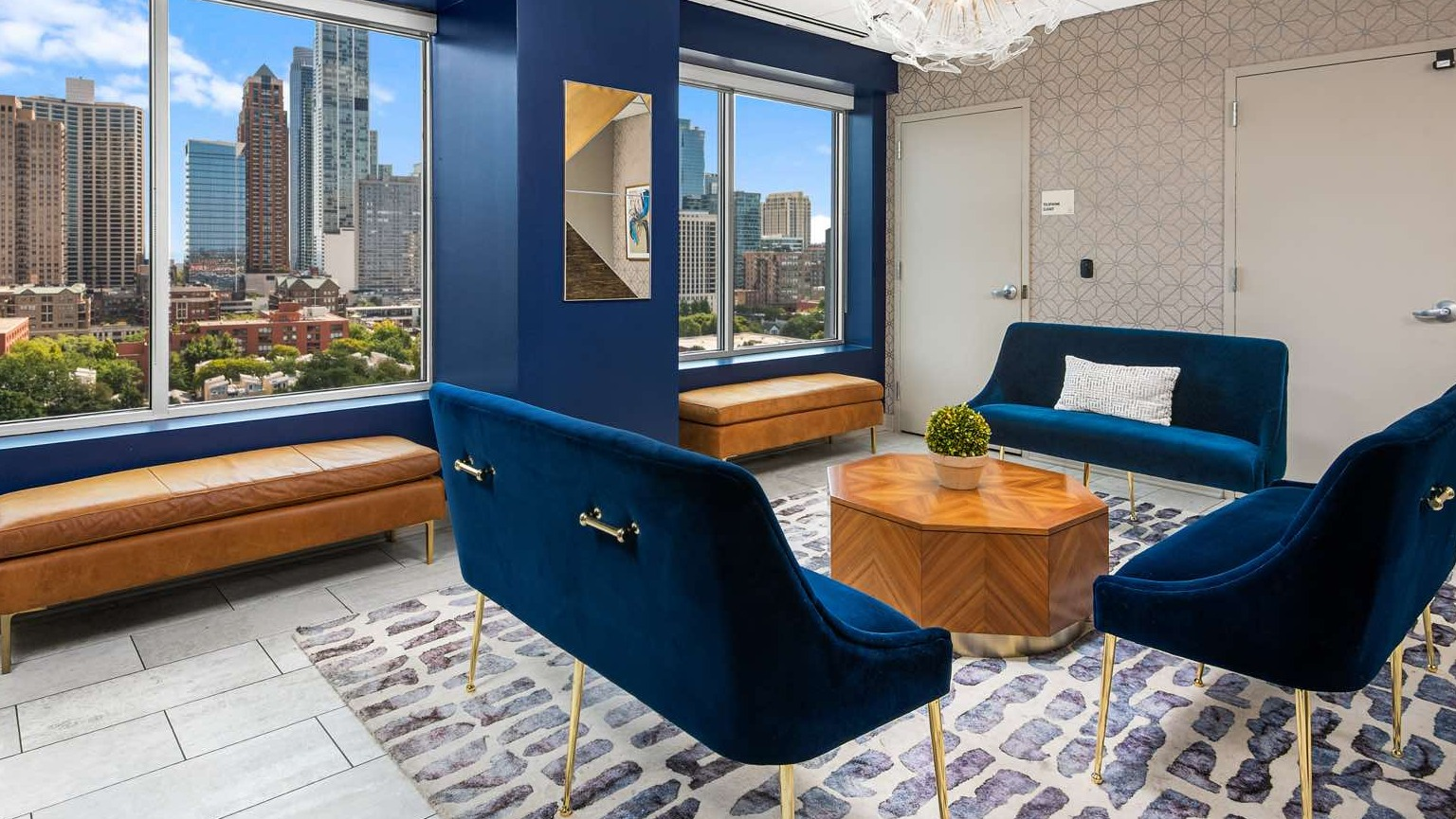 Elegant clubhouse lounge with comfortable blue velvet seating, modern decor, and large windows offering city views at Roosevelt Collection Lofts