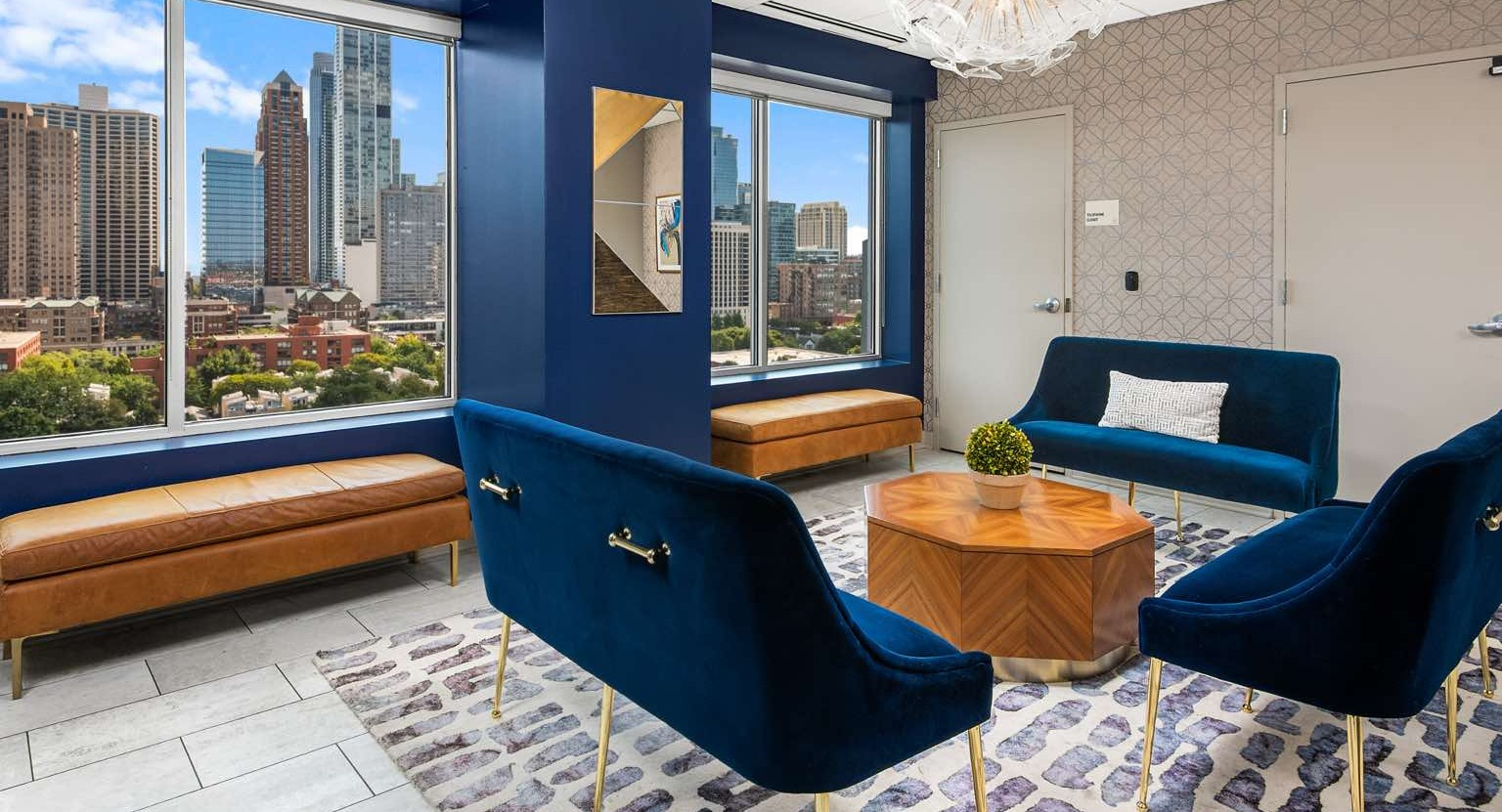 Elegant clubhouse lounge with comfortable blue velvet seating, modern decor, and large windows offering city views at Roosevelt Collection Lofts