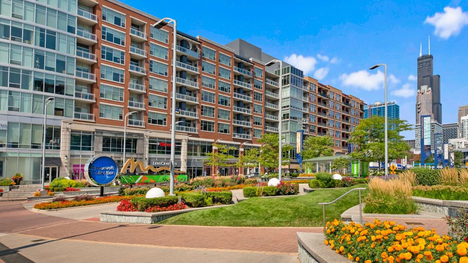Wide exterior view of Roosevelt Collection Lofts showcasing the building's architecture, street-level landscaping, and city backdrop