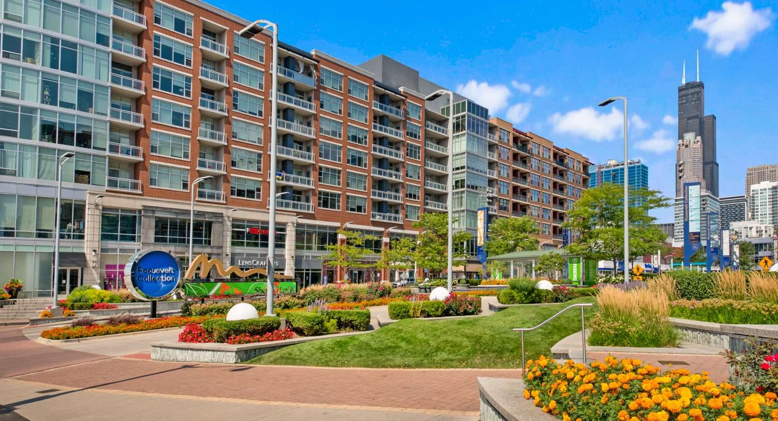 Wide exterior view of Roosevelt Collection Lofts showcasing the building's architecture, street-level landscaping, and city backdrop