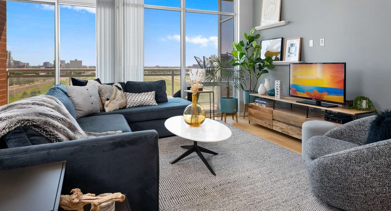 Inviting living room at Roosevelt Collection Lofts in Chicago, featuring a sunny yellow sofa, stylish rug, and expansive windows with city views