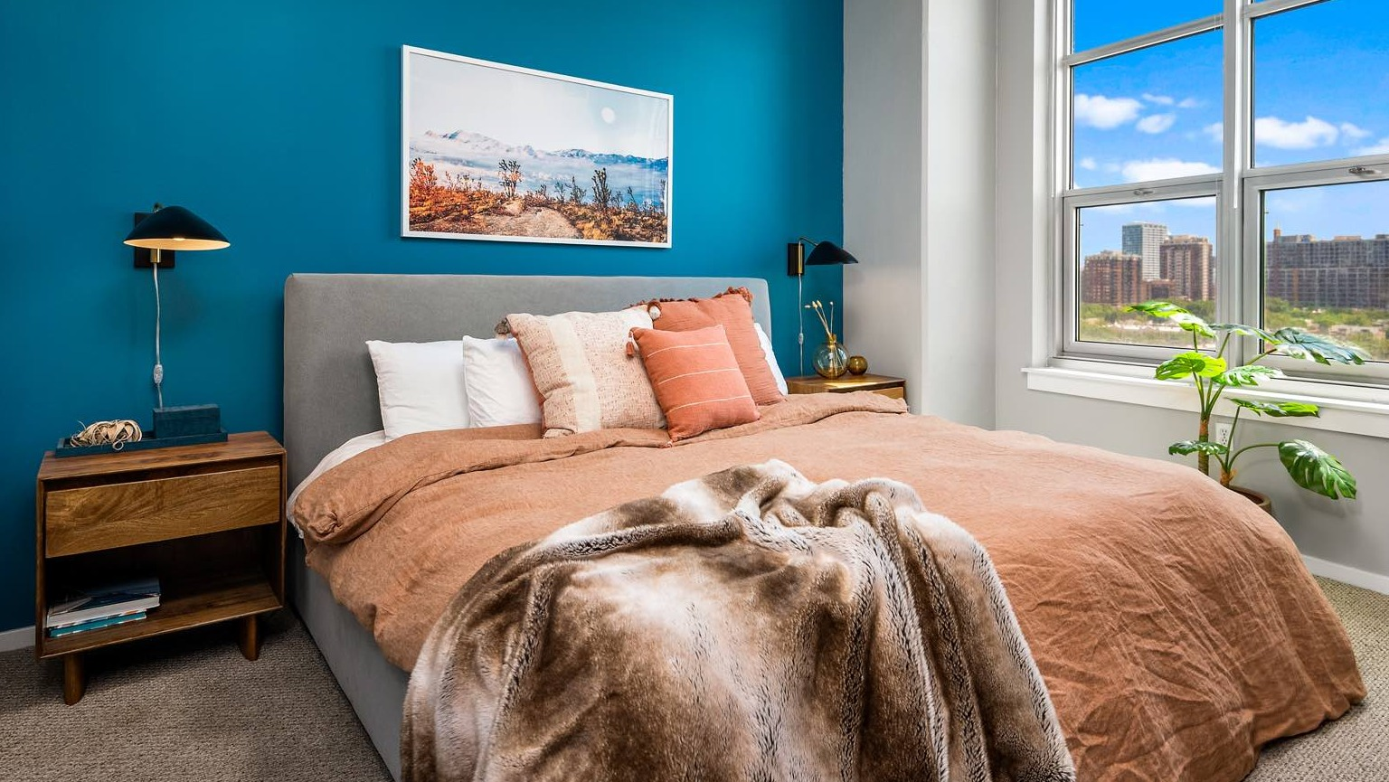 Cozy master bedroom with a vibrant accent wall, comfortable bed, and large windows offering city views at Roosevelt Collection Lofts