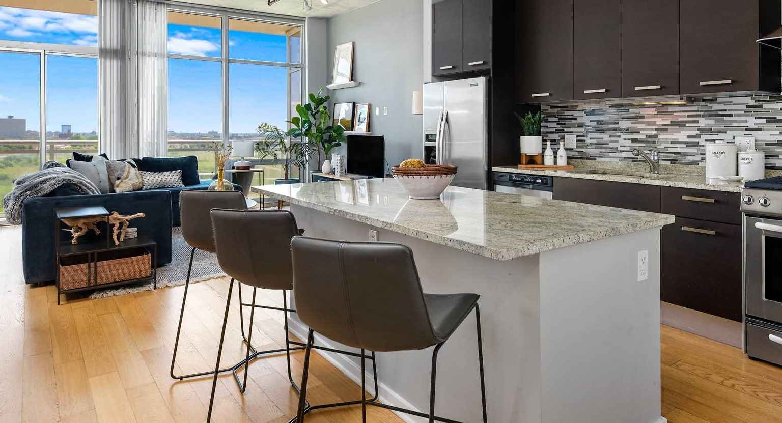 Spacious open-concept living area at Roosevelt Collection Lofts in Chicago, featuring a modern kitchen island, comfortable sofa, and large windows