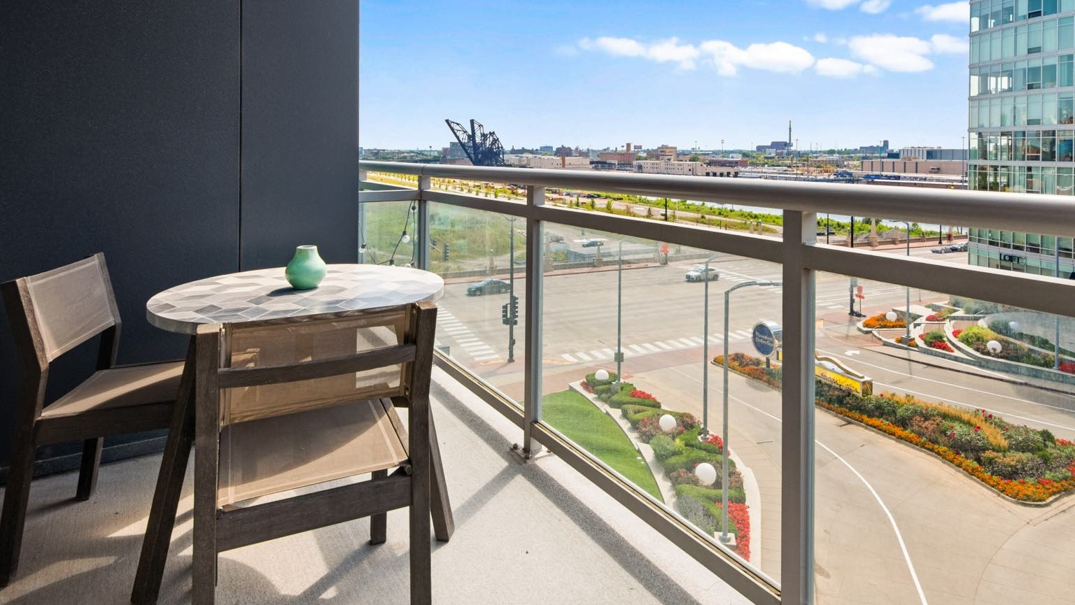 Private apartment balcony with a small table and chairs, offering views of the city street and landscaped areas at Roosevelt Collection Lofts
