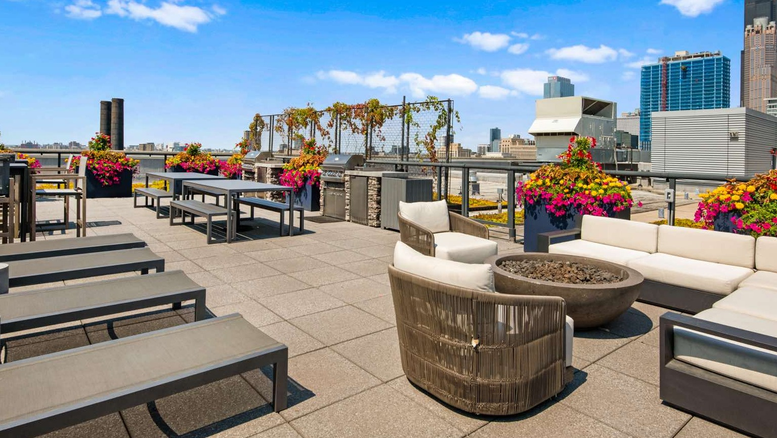 Vibrant rooftop deck with ample seating, sun loungers, a fire pit, and stunning Chicago cityscape views at Roosevelt Collection Lofts