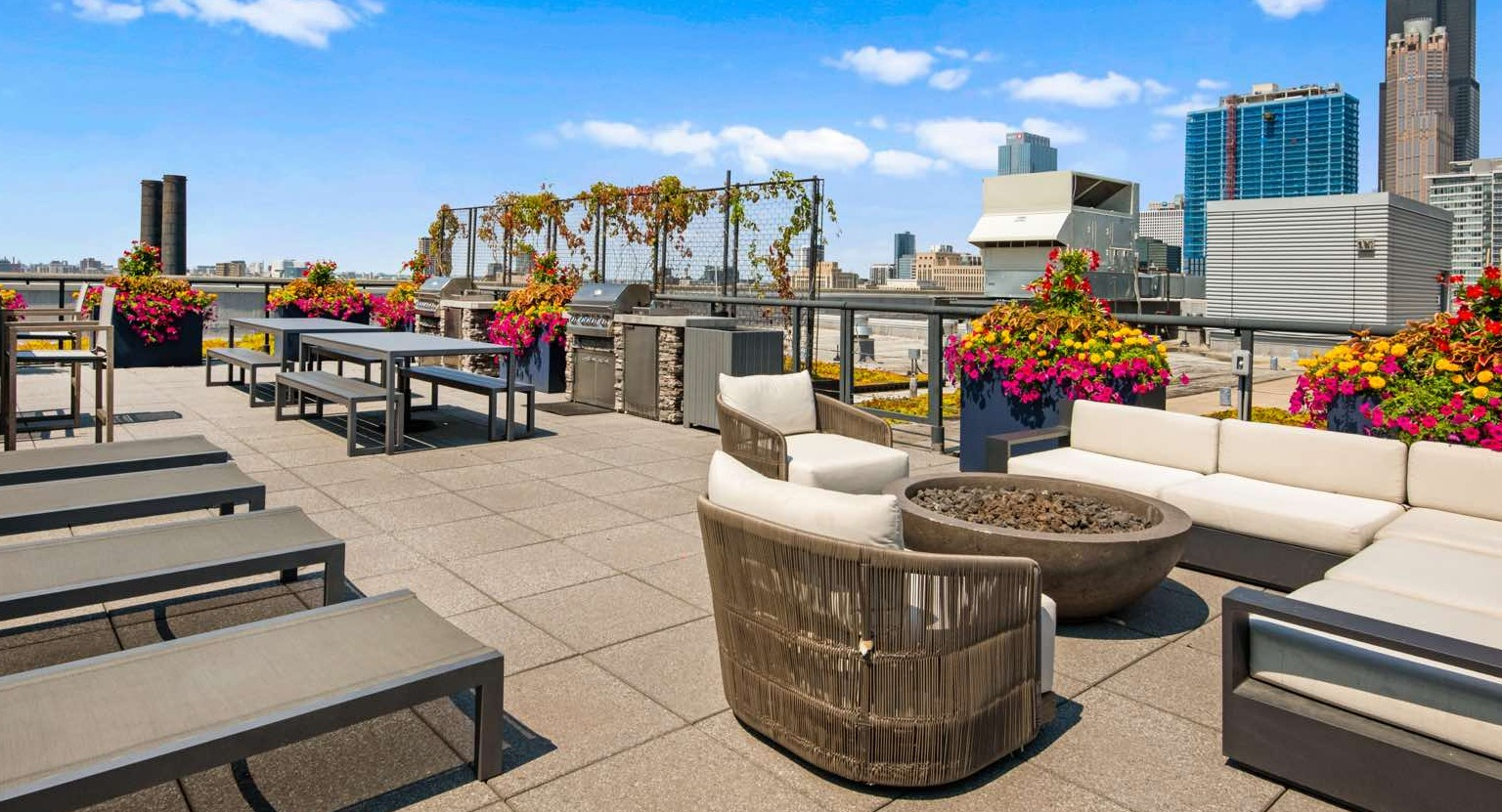 Vibrant rooftop deck with ample seating, sun loungers, a fire pit, and stunning Chicago cityscape views at Roosevelt Collection Lofts