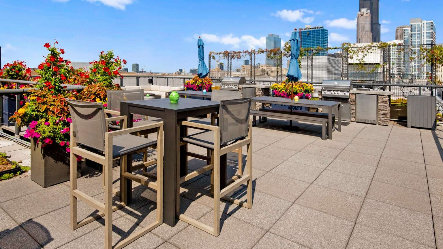 Expansive rooftop deck with grilling stations, high-top dining tables, and panoramic city views, including skyscrapers at Roosevelt Collection Lofts