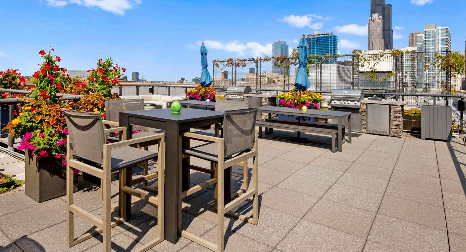 Expansive rooftop deck with grilling stations, high-top dining tables, and panoramic city views, including skyscrapers at Roosevelt Collection Lofts