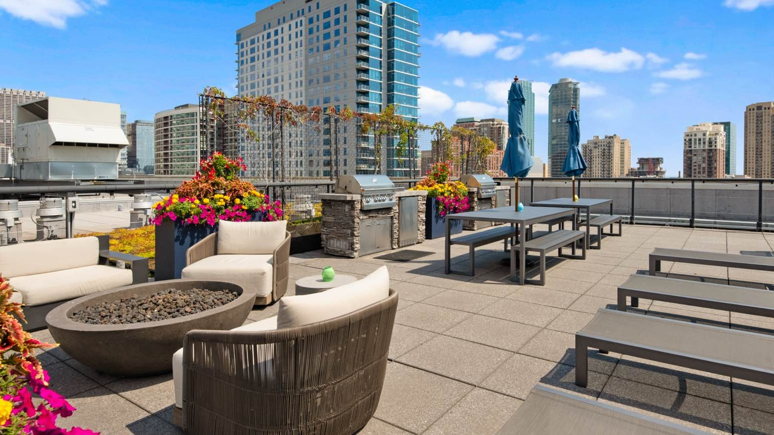 Spacious rooftop lounge area with a cozy fire pit, comfortable seating, sun loungers, and city views at Roosevelt Collection Lofts