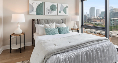 Bright and serene bedroom at Sage West Loop Apartments in Chicago, featuring a comfortable bed, minimalist decor, and expansive city views