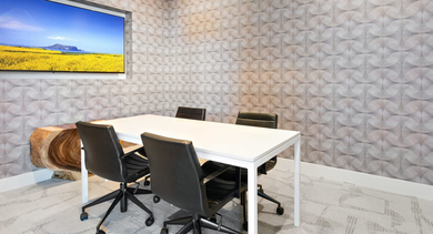 Modern conference room at Sage West Loop Apartments in Chicago, featuring a white table, office chairs, and a large wall-mounted screen