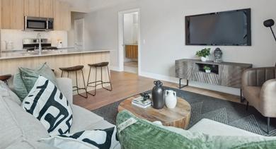 Modern open-concept kitchen and living area at Sage West Loop Apartments in Chicago, featuring a kitchen island, comfortable sofa, and entertainment space