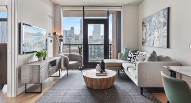 Modern living room at Sage West Loop Apartments in Chicago, featuring a comfortable sofa, stylish decor, and stunning city views