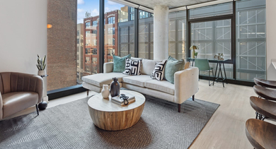 Inviting living room at Sage West Loop Apartments in Chicago, featuring a comfortable sectional sofa, accent chair, and large windows