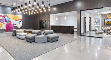 Expansive resident lounge and lobby area at Sage West Loop Apartments in Chicago, featuring modern seating, a reception desk, and vibrant art