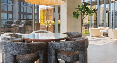 Elegant rooftop dining area at Sage West Loop Apartments in Chicago, featuring a communal table, comfortable chairs, and outdoor grills