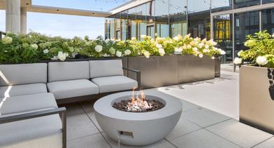 Inviting rooftop terrace at Sage West Loop Apartments in Chicago, featuring a cozy fire pit, comfortable lounge seating, and lush planters