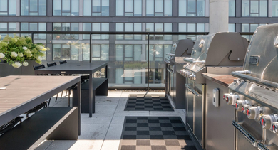 Outdoor rooftop grilling and dining area at Sage West Loop Apartments in Chicago, featuring multiple grills and communal tables