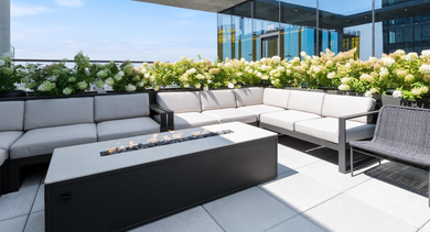 Inviting rooftop lounge at Sage West Loop Apartments in Chicago, featuring a modern fire pit, comfortable sofas, and lush planters