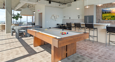 Luxurious sky lounge at Sage West Loop Apartments in Chicago, featuring a pool table, modern kitchen, and stunning panoramic views