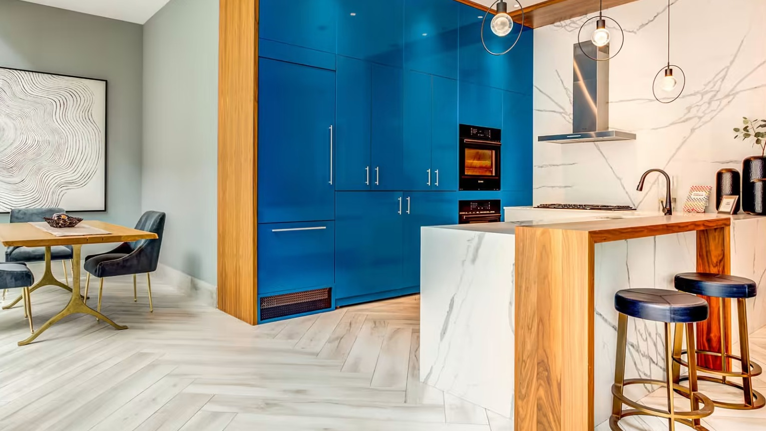 Stylish gourmet kitchen and dining area at Sentral Michigan Avenue in Chicago, featuring bold blue cabinetry, a marble island, and modern dining furniture
